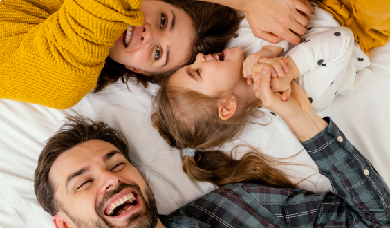 Imagem de uma família deitada no chão sorrindo